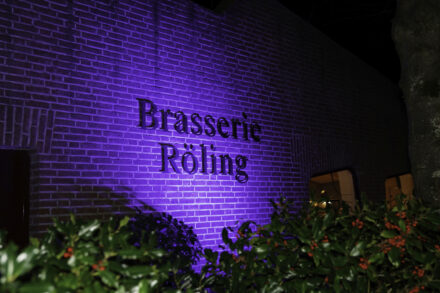 Het logo aan de muur van Brasserie Röling is blauw verlicht