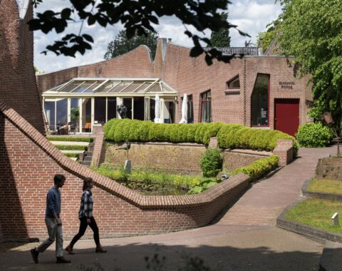 Twee mensen lopen vanaf het museum richting Brasserie Röling