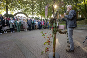Een man spreekt een menigte toe tijdens de opening van Power to the Flower
