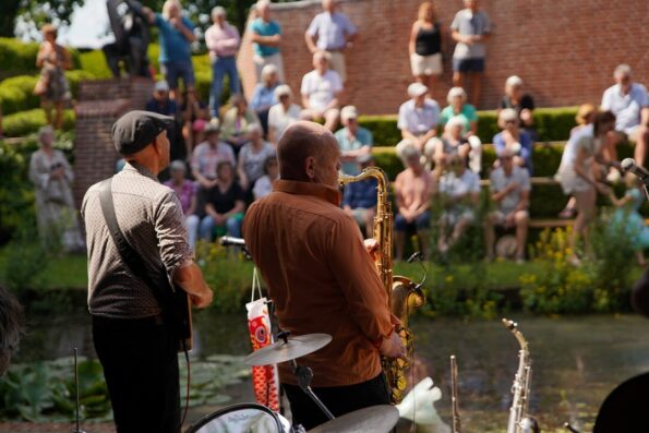 Muzikanten spelen op het buitenpodium met toeschouwend publiek
